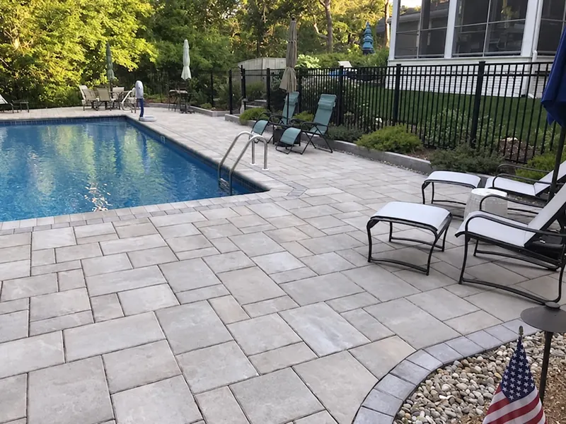 Paver pool deck with lounge chairs around a swimming pool